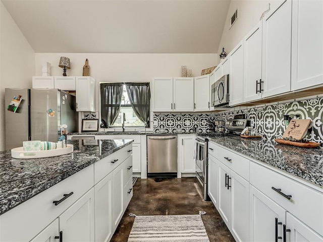 kitchen with white cabinets, stainless steel appliances, dark stone counters, and sink