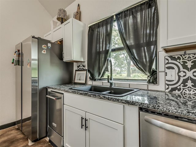 kitchen with white cabinets, stainless steel appliances, stone counters, and sink