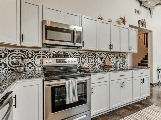 kitchen featuring white cabinets, appliances with stainless steel finishes, and dark stone counters