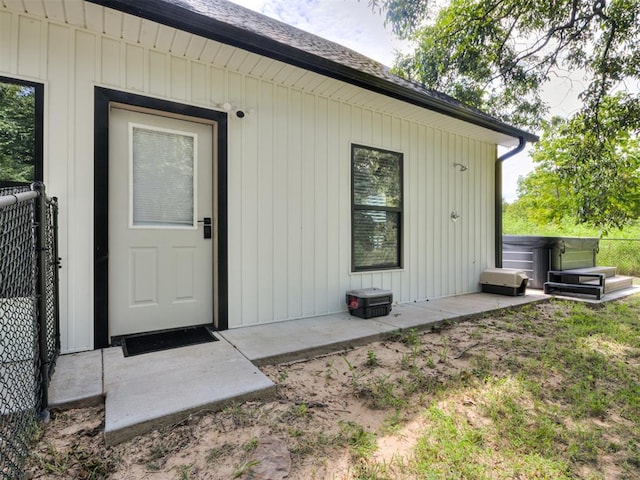 view of exterior entry with a patio and a hot tub