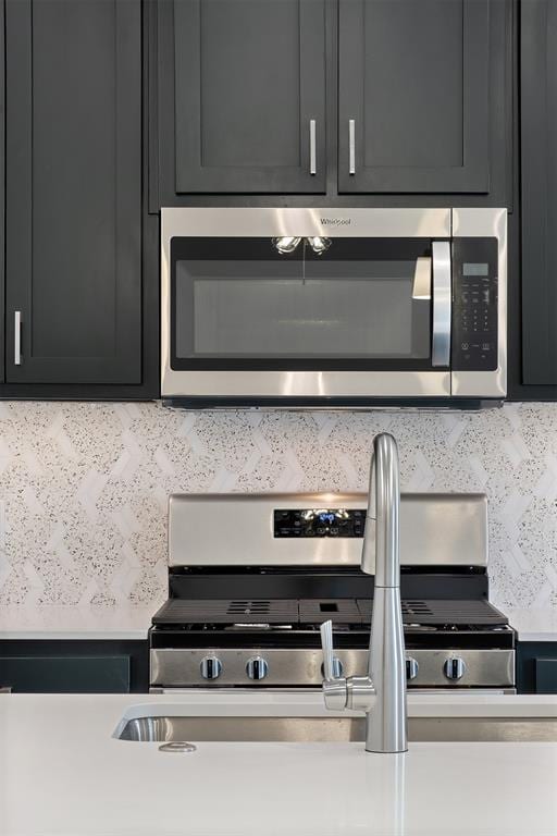 2144 Emily Rae Ln, Blanchard, OK 73010 - kitchen view of stainless steel appliances, decorative backsplash, dark cabinets, and light countertops
