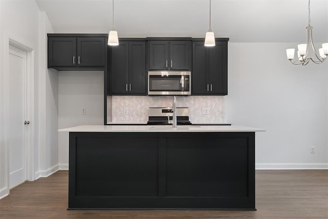 2144 Emily Rae Ln, Blanchard, OK 73010 - kitchen with appliances with stainless steel finishes, light countertops, decorative backsplash, a kitchen island with sink, and dark wood-style floors