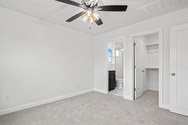 2144 Emily Rae Ln, Blanchard, OK 73010 - unfurnished bedroom with a walk in closet, light colored carpet, a closet, connected bathroom, and a ceiling fan