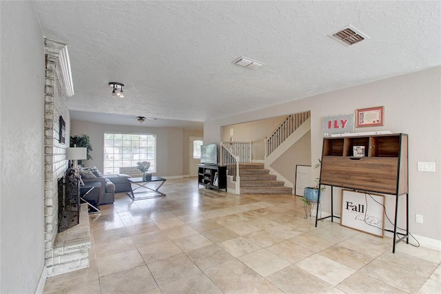 interior space featuring ceiling fan, a textured ceiling, and a brick fireplace