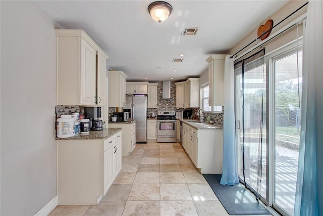 kitchen with sink, wall chimney exhaust hood, decorative backsplash, light stone countertops, and appliances with stainless steel finishes