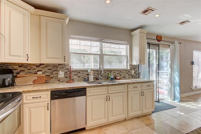 kitchen featuring decorative backsplash, appliances with stainless steel finishes, cream cabinetry, and sink