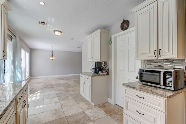 kitchen featuring pendant lighting, light stone countertops, and backsplash