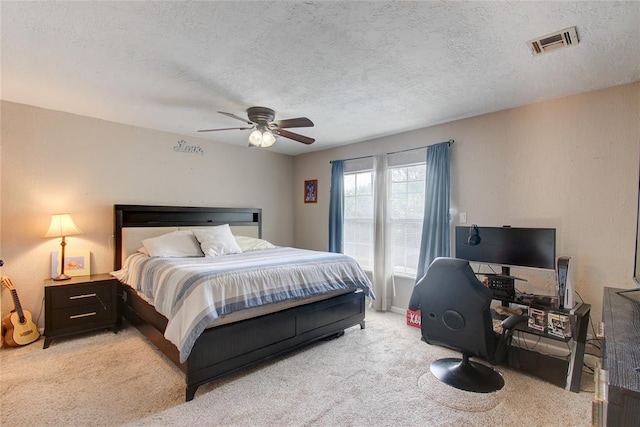 carpeted bedroom featuring ceiling fan and a textured ceiling