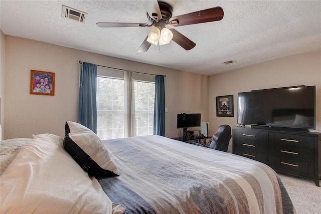 carpeted bedroom featuring ceiling fan and a textured ceiling