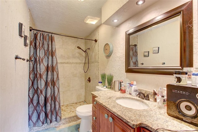 bathroom with vanity, curtained shower, toilet, and a textured ceiling