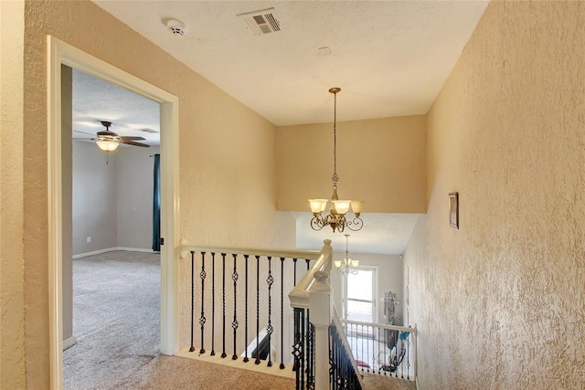 hall featuring carpet flooring and an inviting chandelier