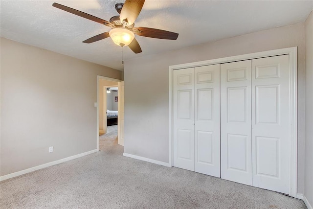 unfurnished bedroom with light carpet, a textured ceiling, a closet, and ceiling fan