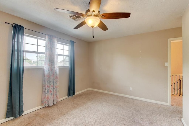 unfurnished room featuring a textured ceiling, ceiling fan, and light carpet