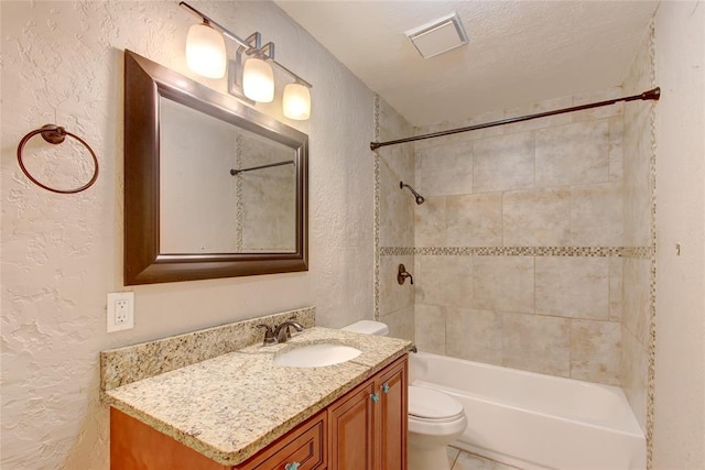 full bathroom featuring vanity, tiled shower / bath combo, a textured ceiling, and toilet