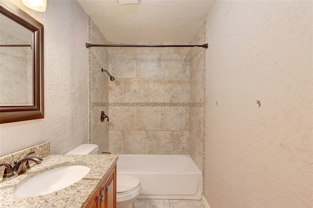 full bathroom with a textured ceiling, vanity, toilet, and tiled shower / bath