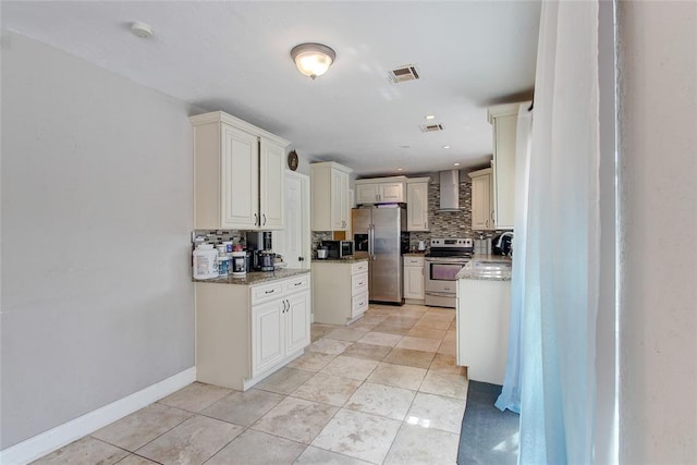 kitchen featuring tasteful backsplash, light stone counters, wall chimney exhaust hood, and stainless steel appliances