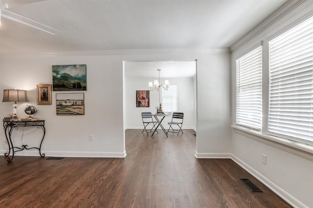 interior space with dark hardwood / wood-style flooring, ornamental molding, and an inviting chandelier