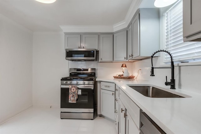 kitchen featuring sink, gray cabinets, light tile patterned floors, ornamental molding, and stainless steel appliances