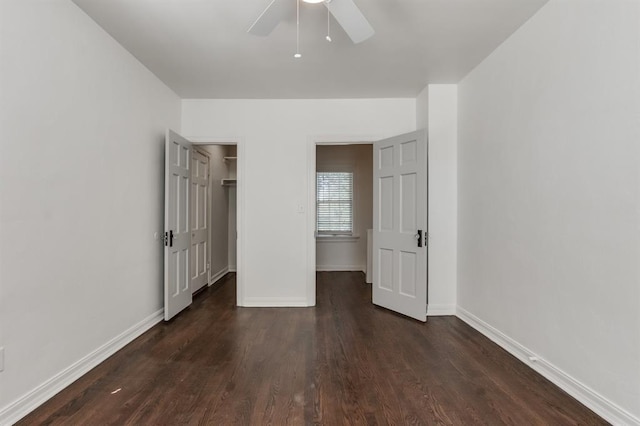 unfurnished bedroom with ceiling fan, a walk in closet, dark wood-type flooring, and a closet