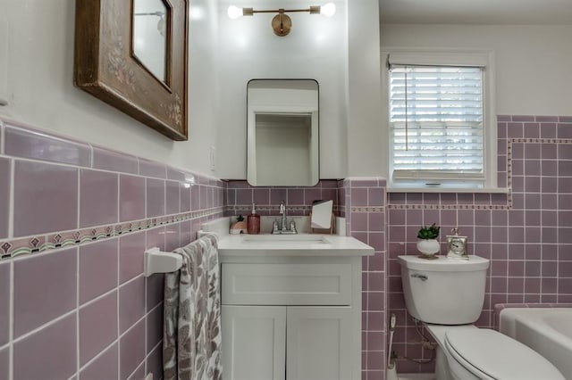 bathroom featuring vanity, a bath, tile walls, and toilet