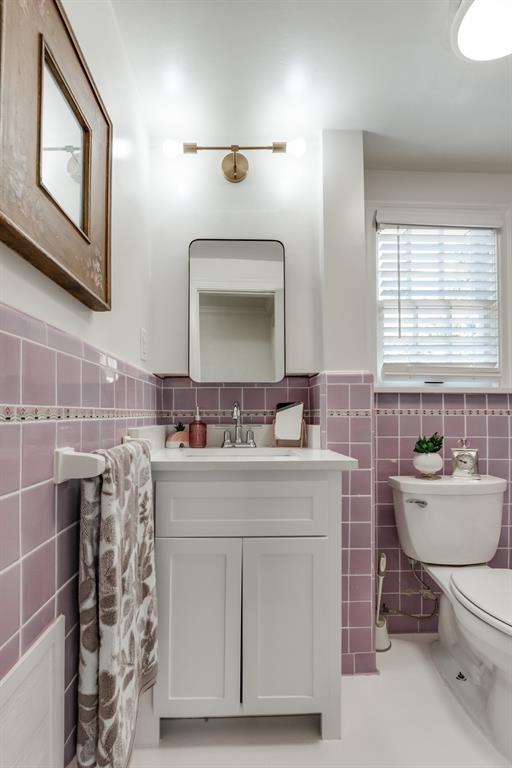 bathroom featuring vanity, tile walls, and toilet