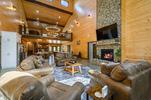 living room with wood walls, high vaulted ceiling, a stone fireplace, beamed ceiling, and a notable chandelier