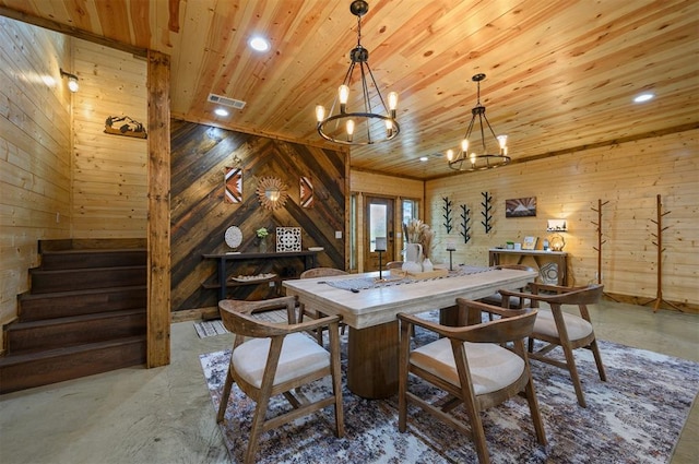 dining area with concrete flooring, wooden ceiling, a notable chandelier, and wood walls