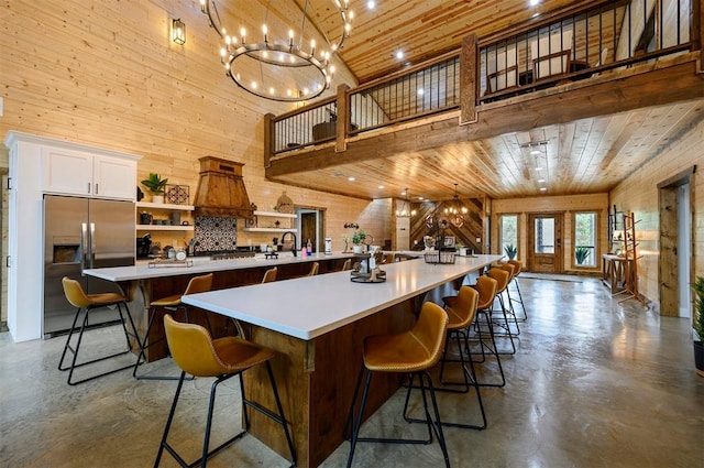 kitchen with a large island, built in refrigerator, a towering ceiling, a breakfast bar, and wood ceiling