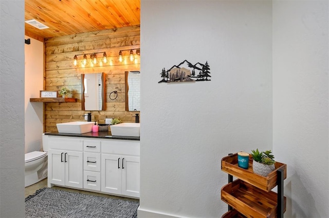 bathroom featuring vanity, toilet, wooden ceiling, and wood walls