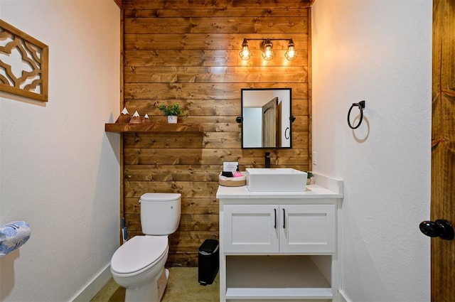 bathroom with vanity, wood walls, and toilet