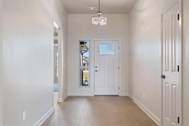 entrance foyer with light hardwood / wood-style flooring and a notable chandelier