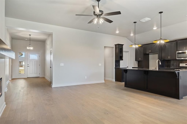 kitchen featuring a kitchen breakfast bar, light hardwood / wood-style flooring, decorative backsplash, decorative light fixtures, and range