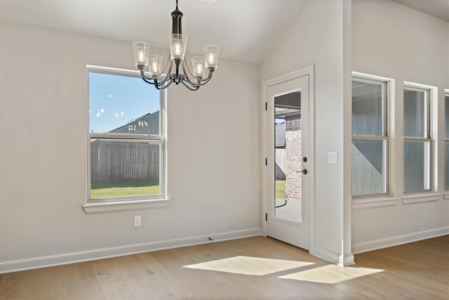 interior space with light wood-type flooring, a wealth of natural light, and an inviting chandelier