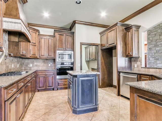 kitchen with light tile patterned floors, light stone counters, ornamental molding, decorative backsplash, and appliances with stainless steel finishes