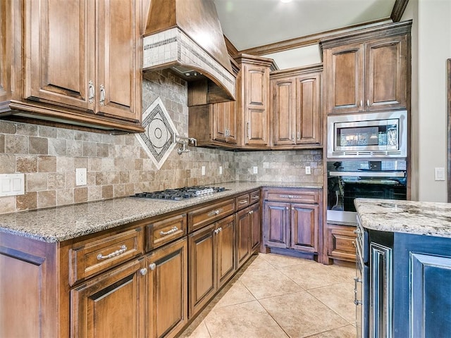 kitchen with custom range hood, light stone counters, tasteful backsplash, stainless steel appliances, and light tile patterned floors