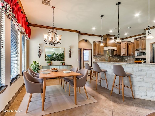 dining area featuring arched walkways, visible vents, light tile patterned floors, and ornamental molding