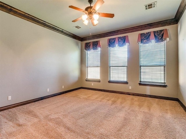 carpeted empty room with visible vents, ceiling fan, baseboards, and ornamental molding