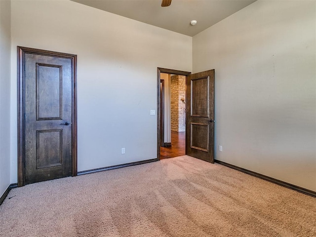 carpeted empty room with baseboards and ceiling fan