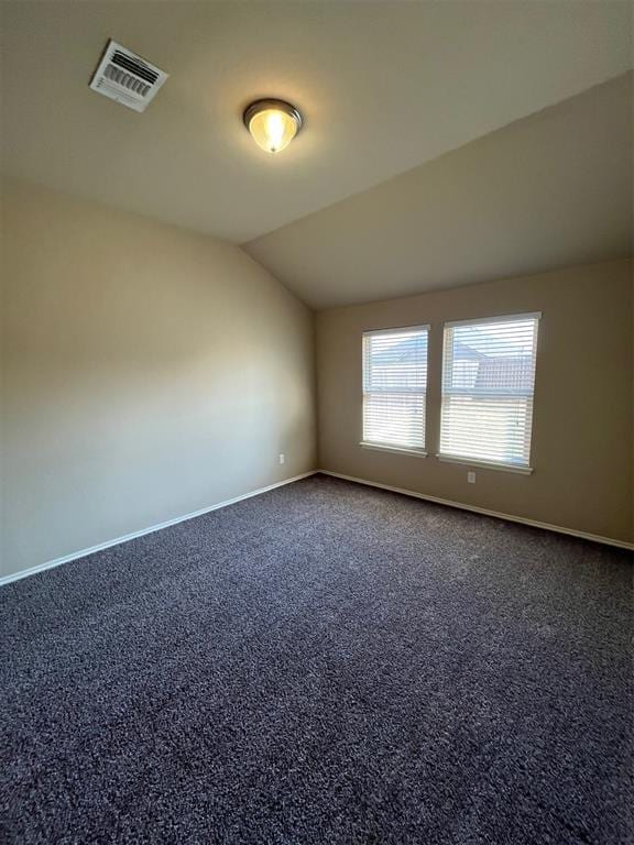 empty room featuring dark carpet and lofted ceiling