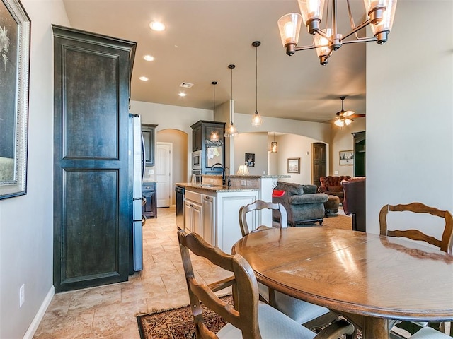 dining area with sink and ceiling fan with notable chandelier