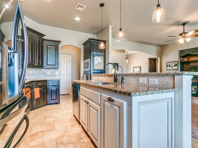 kitchen with pendant lighting, a center island with sink, sink, ceiling fan, and stainless steel appliances