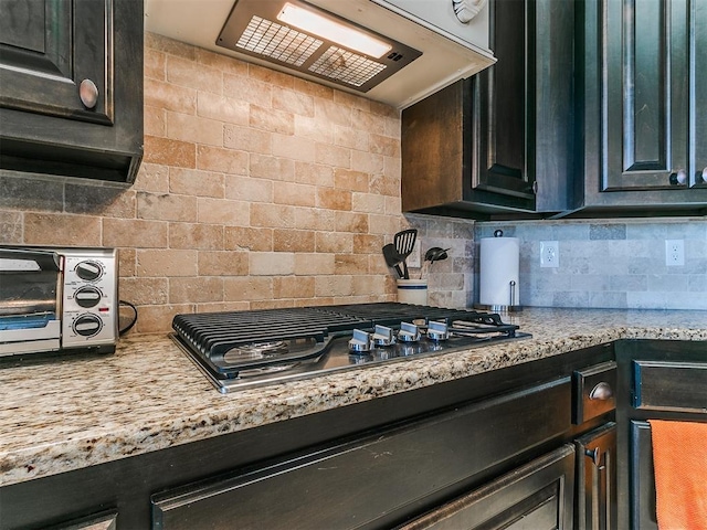 kitchen with decorative backsplash, extractor fan, and stainless steel gas cooktop