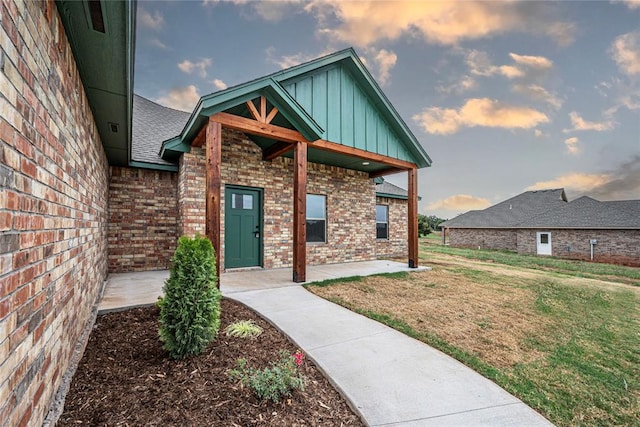 exterior entry at dusk featuring a lawn