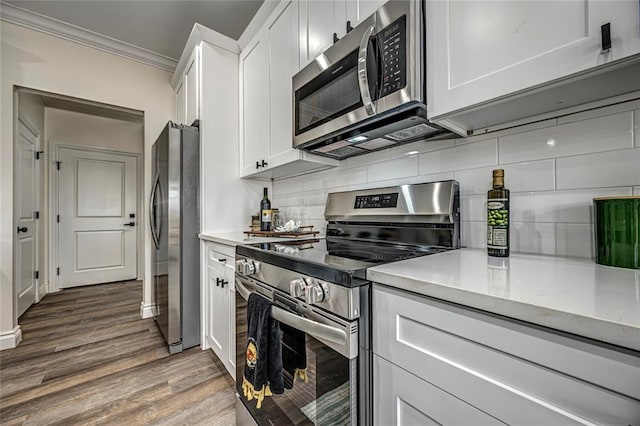 kitchen featuring white cabinetry, crown molding, hardwood / wood-style flooring, and appliances with stainless steel finishes