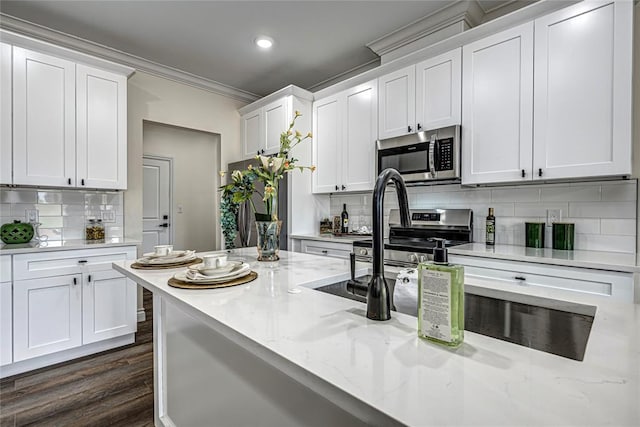 kitchen featuring white cabinetry, tasteful backsplash, dark hardwood / wood-style floors, appliances with stainless steel finishes, and ornamental molding