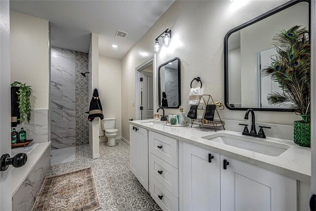 bathroom with tiled shower, vanity, and toilet