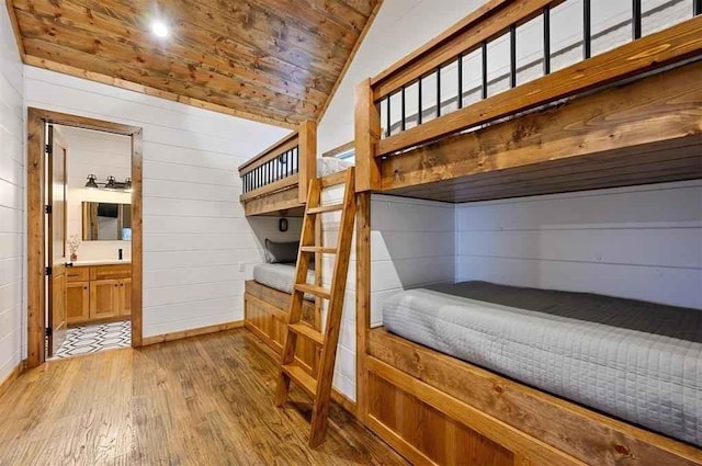 bedroom with hardwood / wood-style floors, wooden ceiling, wooden walls, and vaulted ceiling