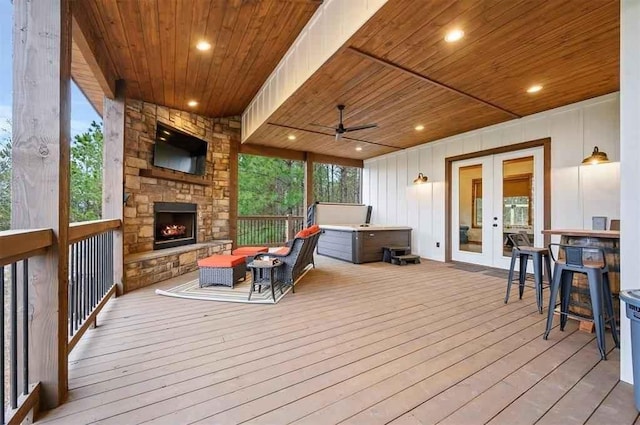 wooden terrace featuring an outdoor living space with a fireplace, ceiling fan, exterior bar, and french doors