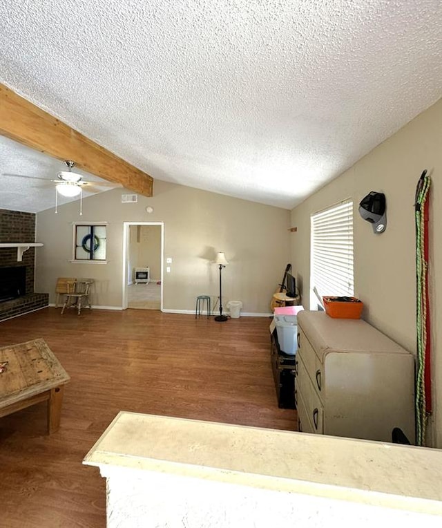 living room featuring ceiling fan, hardwood / wood-style floors, lofted ceiling with beams, and a textured ceiling