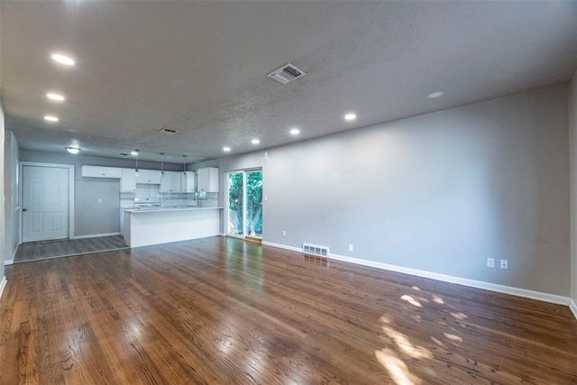 unfurnished living room featuring dark hardwood / wood-style flooring and a textured ceiling